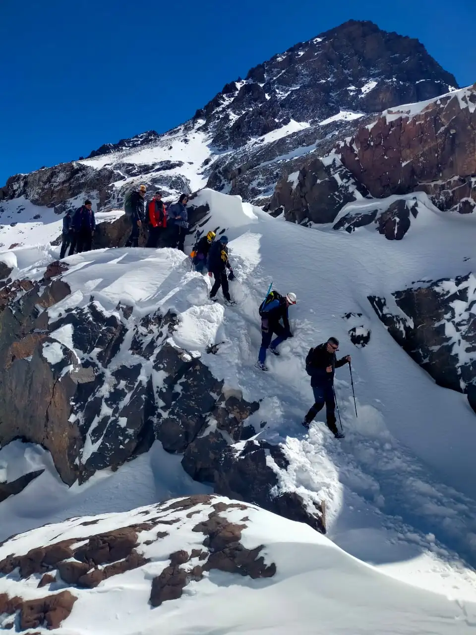 Hikers ascending Mount Toubkal's rocky trail at sunrise, High Atlas